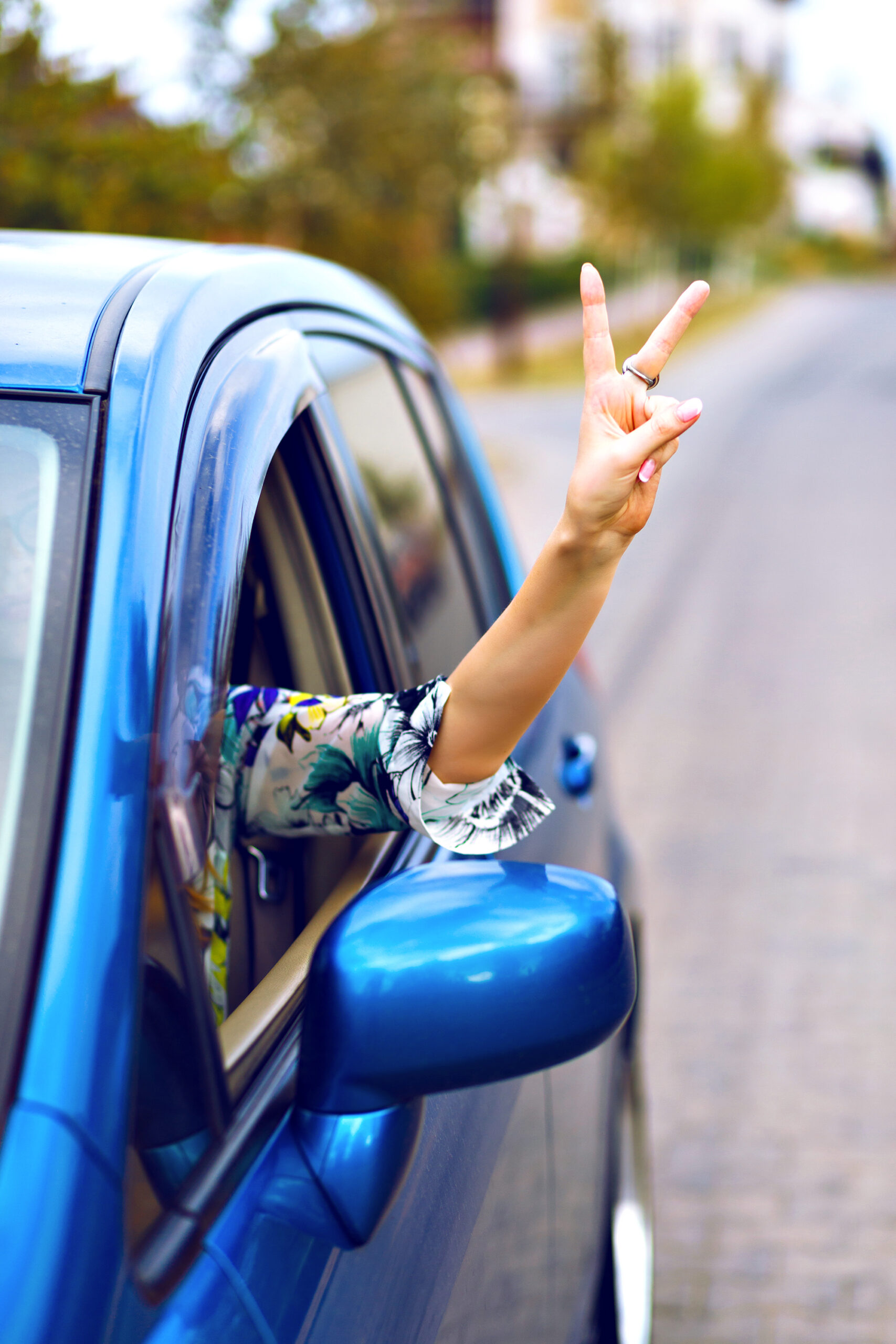 signe victoire conductrice voiture bleue